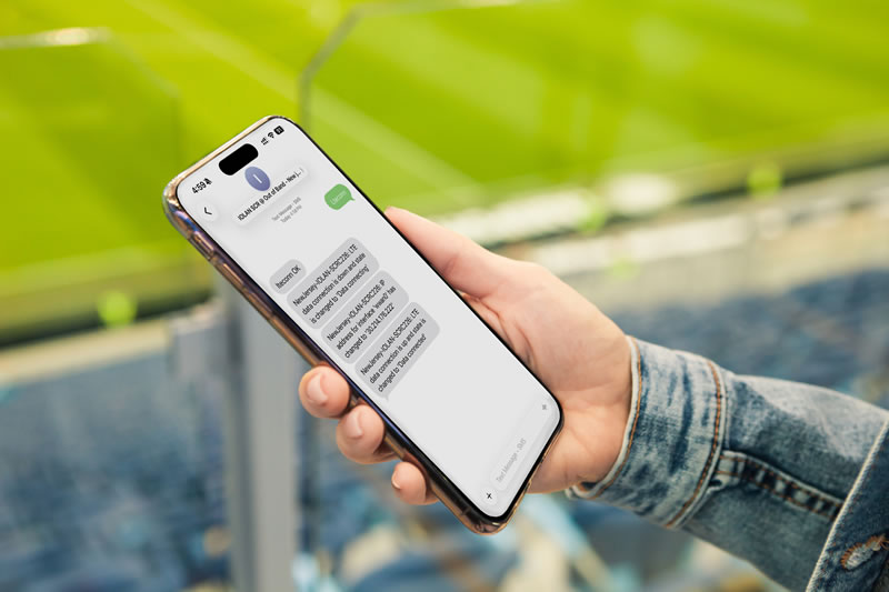 Mano che tiene uno smartphone in uno stadio sportivo mentre invia messaggi di testo a IOLAN SCRC per abilitare una connessione cellulare